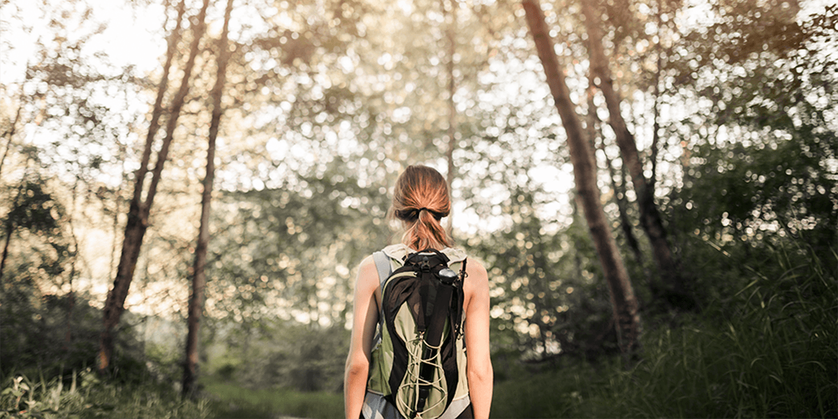 female-hiker-standing-green-forest (1)